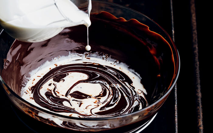 Jar pouring milk over melted chocolate