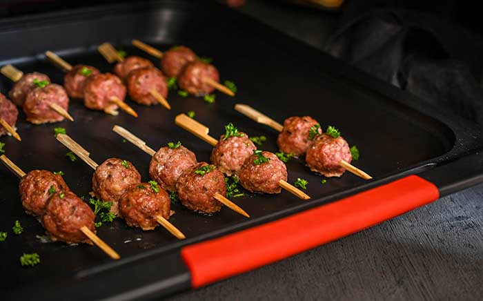 Meatballs skewers placing on an oven tray to cook