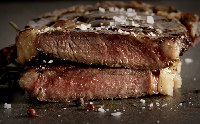 Two pieces of meat with flakes of salt over and cooked on a barbecue