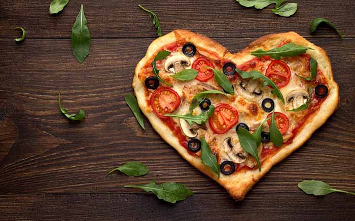 Pizza con aceitunas negras, albahaca, tomate y forma de corazón