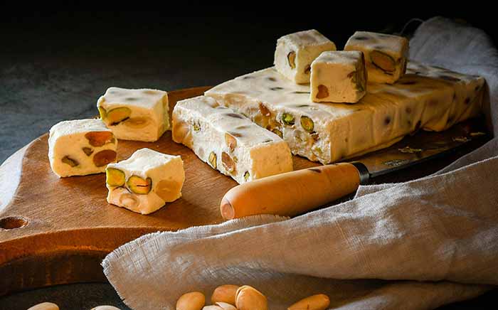 Turrón con pistachos y frutos secos servido sobre tabla de madera