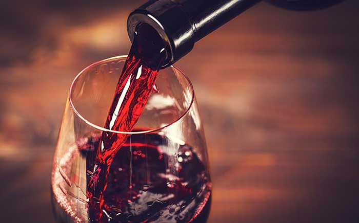 Botella de vino tinto sirviendo el vino en una copa