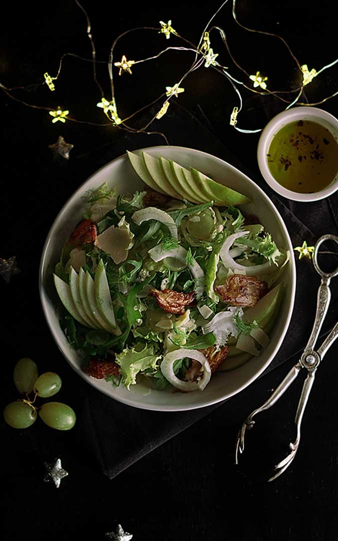 Vegan Christmas salad in a white plate with LED lights and green grapes from the top