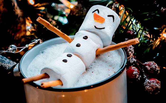 Hombre de nieve sonriente hecho de nubes de azúcar en un tazón de Navidad
