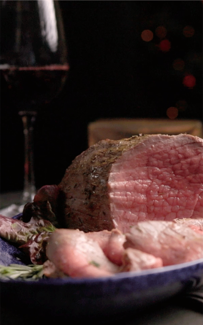 roast beef in an oven platter with a glass of wine on the background